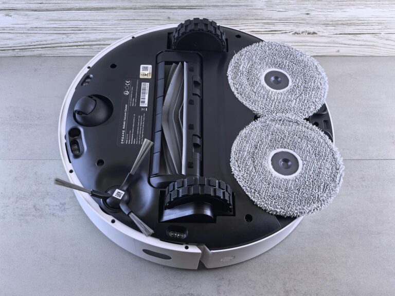 Detailed view of a robotic vacuum cleaner's underside showing brushes and wheels.