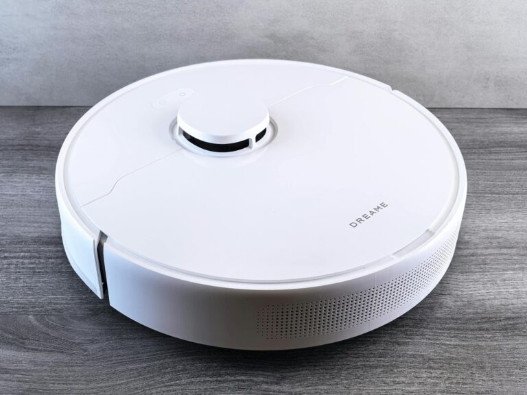 High-angle view of a sleek white robotic vacuum cleaner on a wooden floor, perfect for smart home setups.