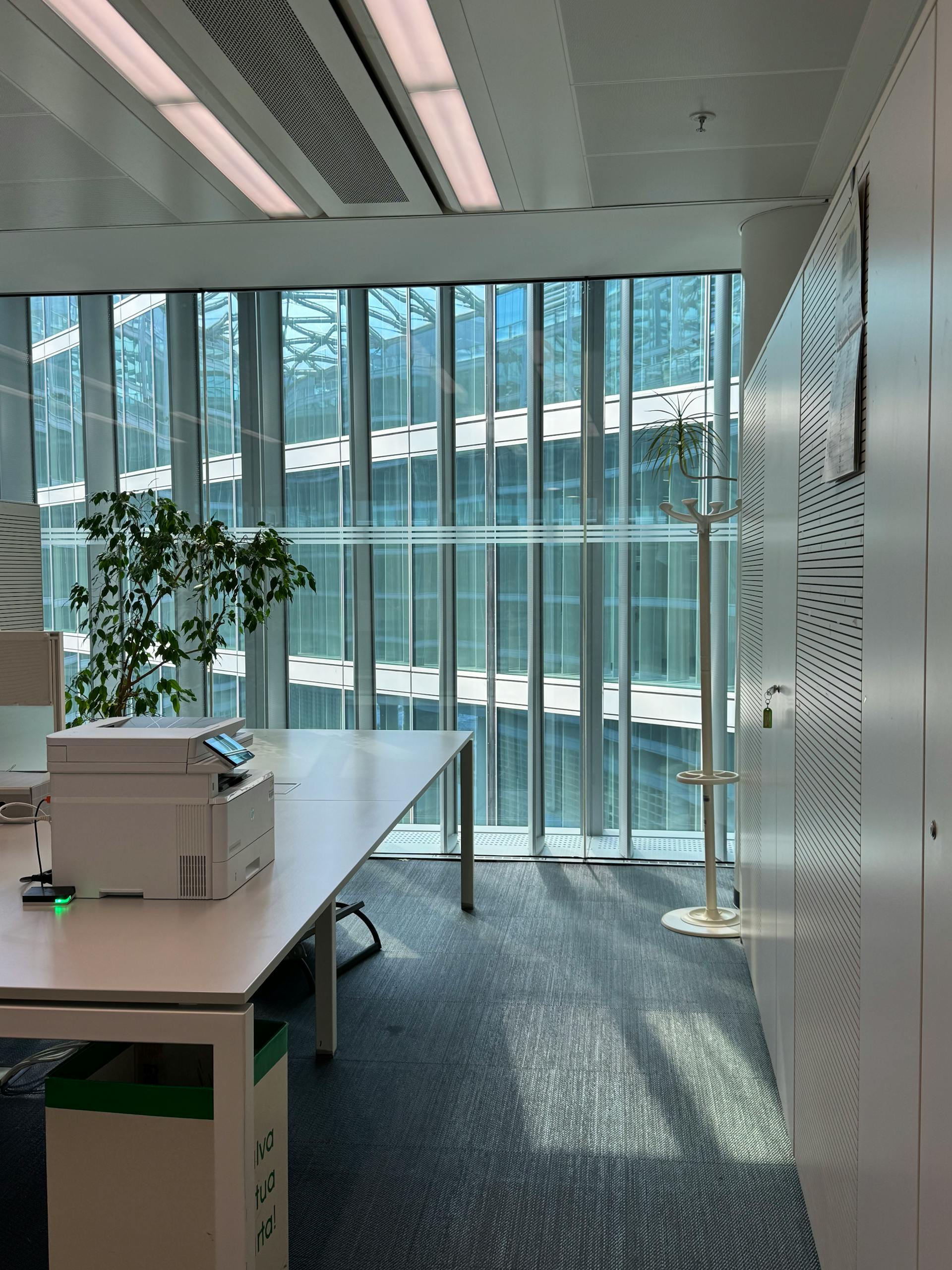 Bright office space in Milan featuring large windows, modern furniture, and natural lighting.